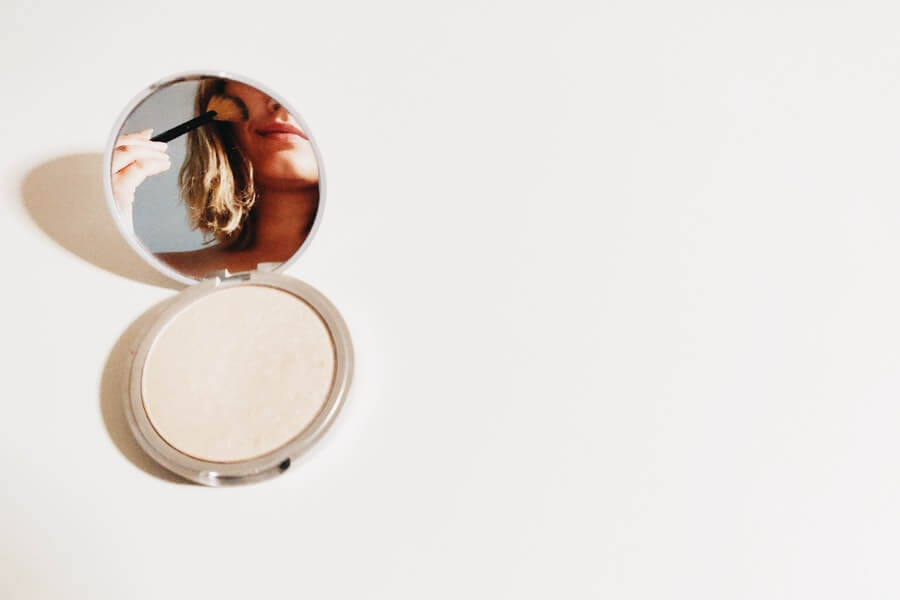 powder compact on a table with woman in mirror