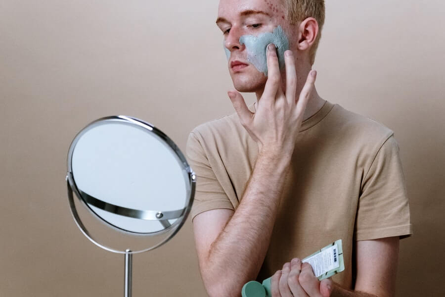 a man applying a facial treatment to answer 'Can Moisturiser Cause Acne?'