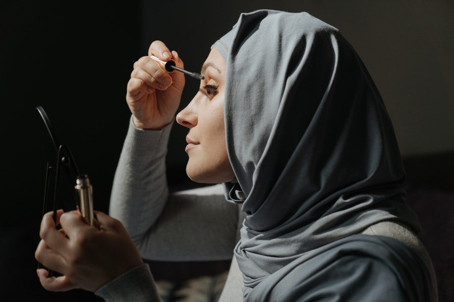 a woman applying makeup to mask eyelash extensions