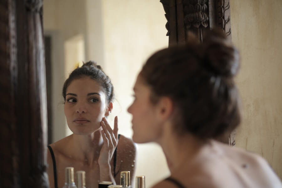 woman checking her face for pimples