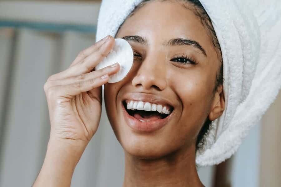 woman using makeup remover on her eyes showing how to remove eyelash extensions at home