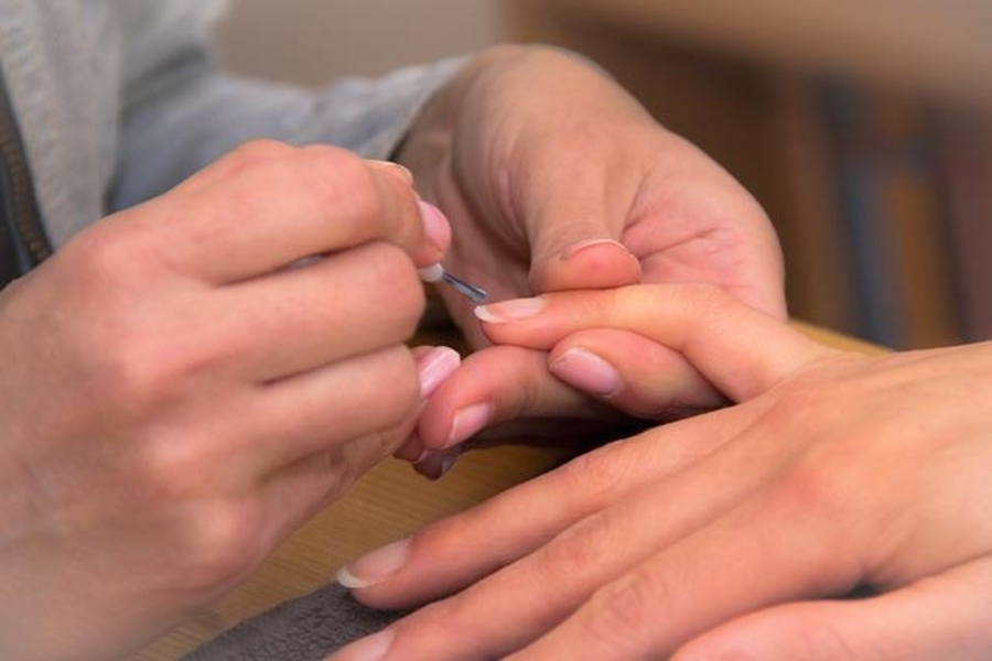 person applying base coat for gel nails at home