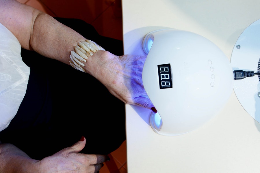 person using UV lamp to cure gel nails at home