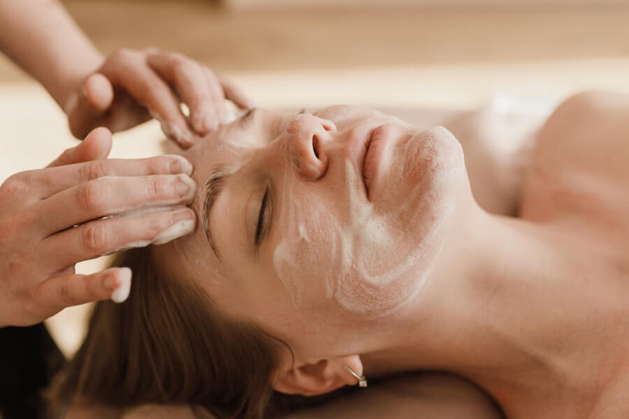 an esthetician applying a facial mask to a client