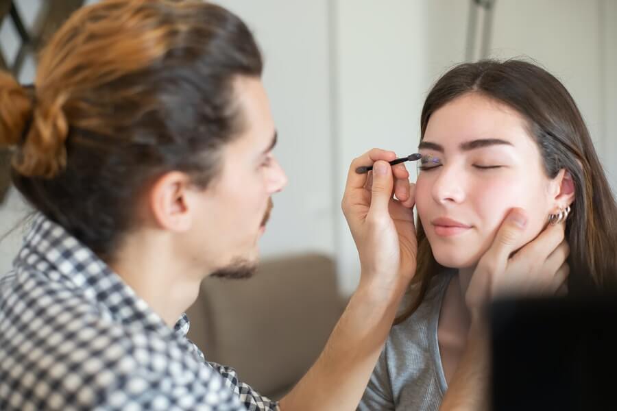 a male makeup artist applying eye shadow to a client